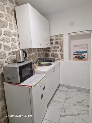 a small kitchen with white cabinets and a microwave at Bond studios- Old town in Kotor
