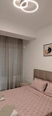 a bedroom with a bed with a pink comforter at South Side Apartment in Podgorica