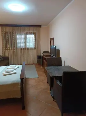 a room with a bed and a table and a television at Villa Roselina By Beatrix in Budva