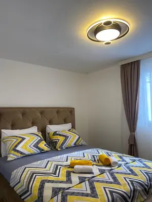 a bedroom with a bed with a yellow and blue blanket at Vucinic Studio Apartment in Cetinje