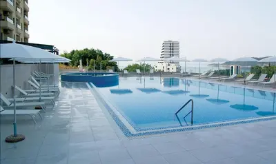 a large swimming pool with chairs and an umbrella at Status-M Аpartments 133 in Becici