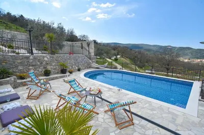a swimming pool with chairs and a table next to a pool at Villa 177 in Tivat