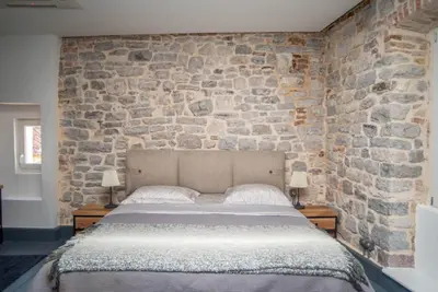 a bed in a room with a stone wall at The Old Town Luxury Apartment by Montenegro Moments in Kotor