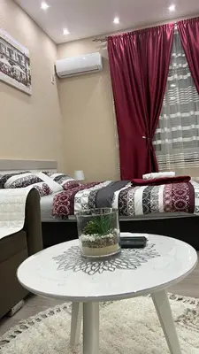a room with two beds and a table in front of it at Apartment Downtown in Podgorica