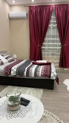 a bedroom with a bed with red curtains and a table at Apartment Downtown in Podgorica