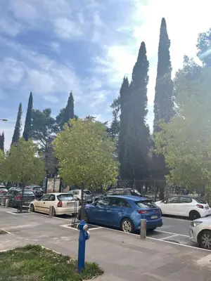 a blue car parked in a parking lot with cars at Apartment Downtown in Podgorica
