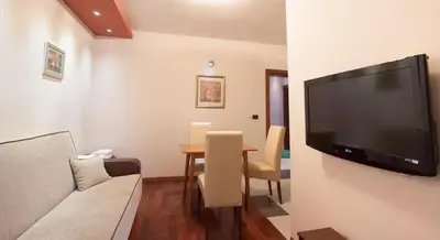 a living room with a couch and a table with a television at Vila Centar in Budva