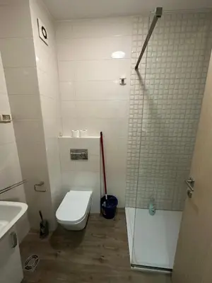 a white bathroom with a toilet and a shower at City kvart 1 bedroom apartment in Podgorica