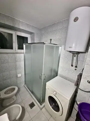 a bathroom with a shower and a toilet and a washing machine at Olive's apartment in Podgorica