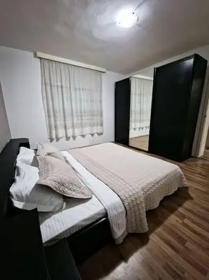 a bedroom with a bed and two windows at Olive's apartment in Podgorica