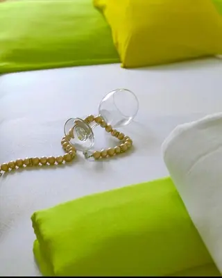 a bead chain on a bed with green pillows at Montenegrina apartment in Ulcinj