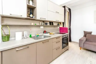 a kitchen with white cabinets and a sink and a chair at Apartman Petra in Pržno
