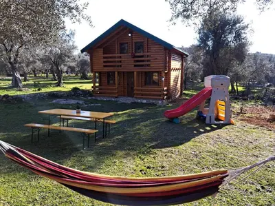 a hammock in front of a log cabin with a playground at Olive & sea, Luxury two bedrooms cabin for 8 in Ulcinj