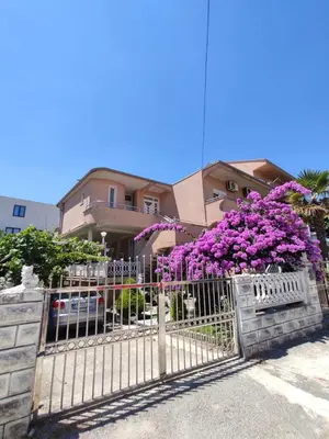 a fence with purple flowers in front of a house at Apartmani Andrijana in Ulcinj
