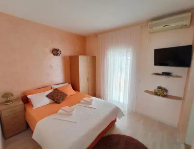 a small bedroom with two beds and a television at Apartmani Andrijana in Ulcinj
