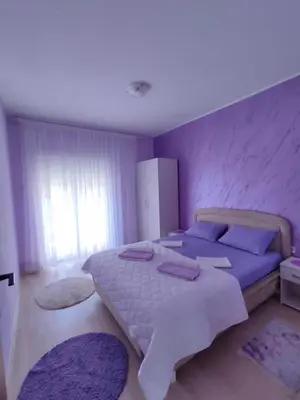 a bedroom with a large bed with purple walls at Apartmani Andrijana in Ulcinj