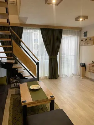a living room with a staircase and a table at Apartman Anna Budva in Budva