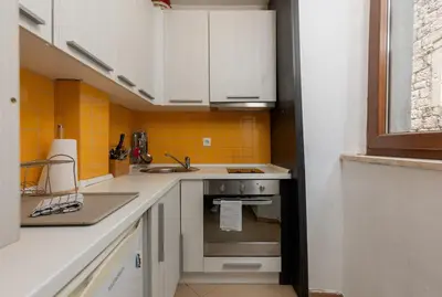 a kitchen with white cabinets and a sink and a stove at Apartment Amigo 2 Old Town Kotor in Kotor