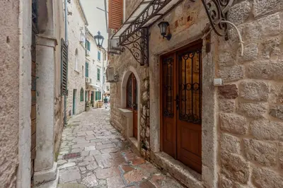 an alley in an old town with a wooden door at Apartment Amigo 2 Old Town Kotor in Kotor