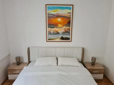 a bed in a bedroom with a painting on the wall at Art Apartment in Podgorica