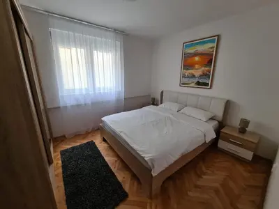 a bedroom with a white bed and a window at Art Apartment in Podgorica