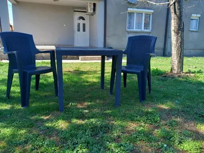 a blue table and four chairs in the grass at Apartment Filipovic in Podgorica