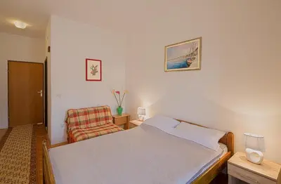 a bedroom with a bed and a chair at Madra Rooms and Apartments in Budva