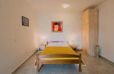 a bedroom with a bed with a yellow blanket at Madra Rooms and Apartments in Budva