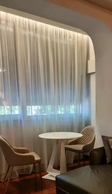 a table and chairs in a room with a window at Rosewood Podgorica in Podgorica