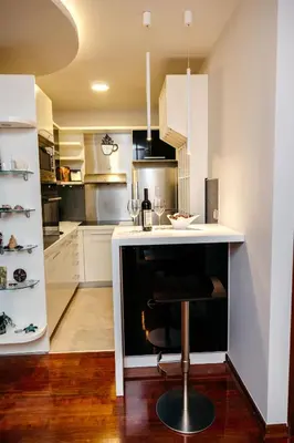 a kitchen with white cabinets and a bar with a stool at Rosewood Podgorica in Podgorica