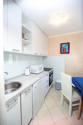a kitchen with white cabinets and a sink and a table at Fairytale 1 and 2 in Budva