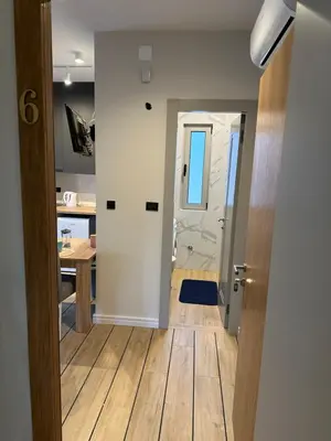 a kitchen with a door leading into a room with a table at Saly Apart in Budva