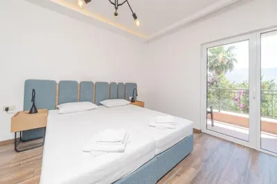 a white bedroom with a large bed and a large window at Apartments Mara Lux in Budva