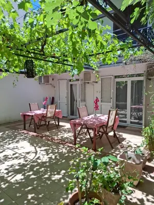 a patio with two tables and chairs under a tree at Splendid Luxury Apartments in Budva