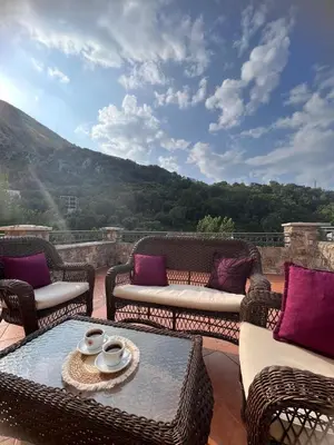 a patio with wicker furniture and a view of a mountain at Vila Reževići in Budva