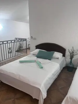 a bed with white sheets and blue pillows on it at Vila Reževići in Budva