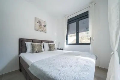 a white bedroom with a bed and a window at Apartment Adriana in Kotor