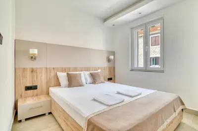 a white bedroom with a large bed with a window at Symphony Apartments Street View in Petrovac na Moru