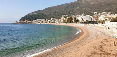 a sandy beach with a town in the background at Symphony Apartments Street View in Petrovac na Moru