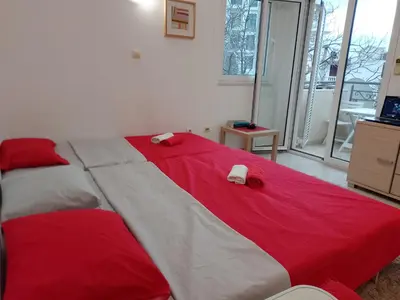 a large bed with red and white sheets in a room at Splendid studio apartment in Becici
