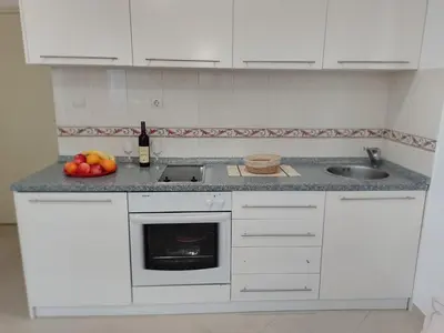 a white kitchen with a sink and a bowl of fruit at Splendid studio apartment in Becici