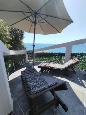 a patio with a table and an umbrella and chairs at Summer Beach House in Ulcinj