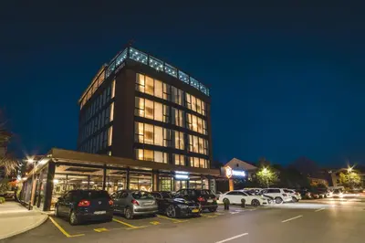 a tall building with cars parked in a parking lot at Bristol Hotel Podgorica in Podgorica
