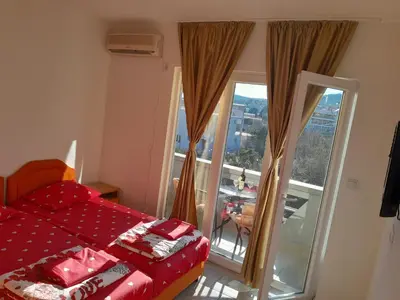a bedroom with a red bed and a balcony at Perper in Sutomore