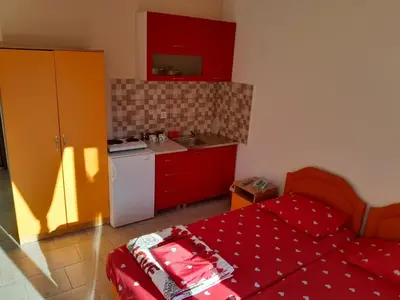 a small kitchen with red cabinets and a red bed at Perper in Sutomore