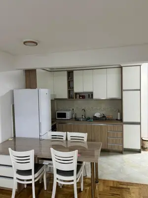 a kitchen with a wooden table and white cabinets at SKY Apartment in Budva
