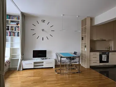 a kitchen with a table and a clock on the wall at Стильная квартира с видом на море и библиотекой in Becici