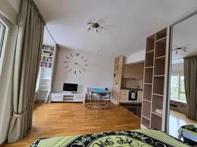 a room with a bed and a clock on the wall at Стильная квартира с видом на море и библиотекой in Becici