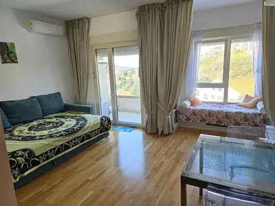 a living room with a bed and a glass table at Стильная квартира с видом на море и библиотекой in Becici