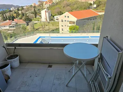 a balcony with a table and a view of a pool at Стильная квартира с видом на море и библиотекой in Becici